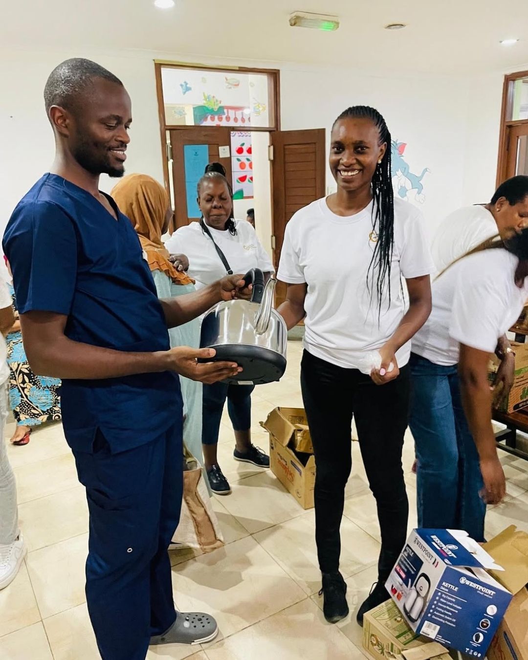 Founder Celina Didas handing a kettle to a doctor at Muhimbili National Hospital